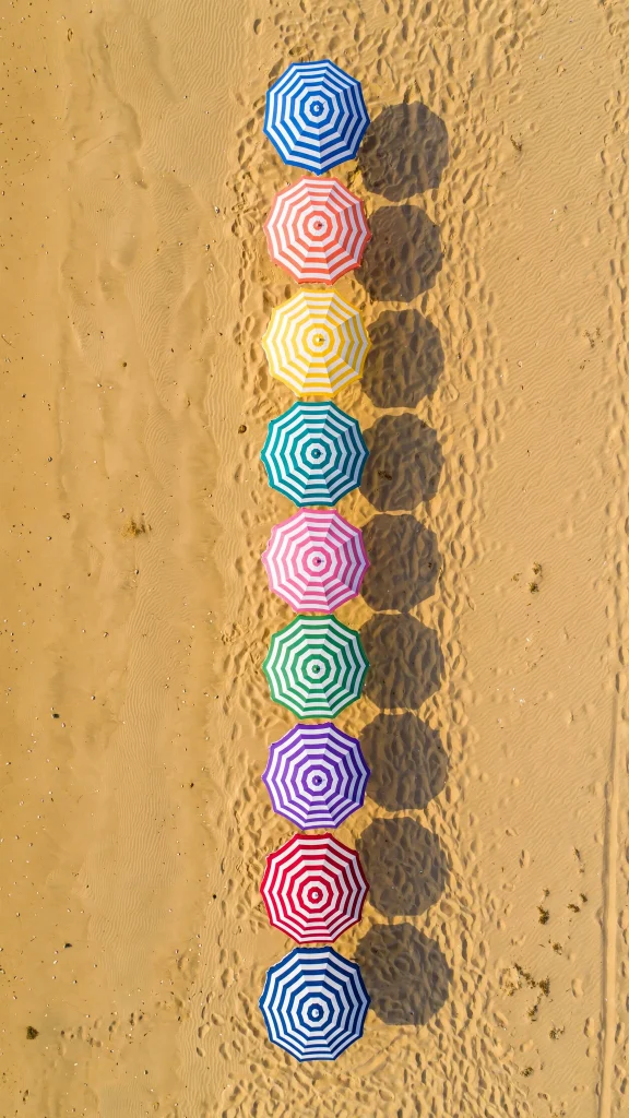 Colorful beach umbrellas in a row from above, wallpaper aesthetic summer